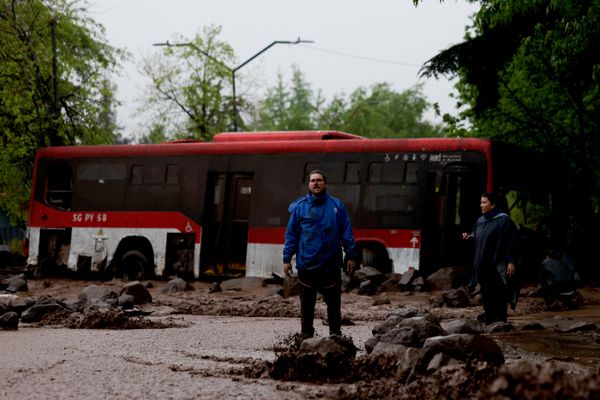 Люди на залитой грязью улице на фоне застрявшего автобуса в Сантьяго. - Sputnik Беларусь