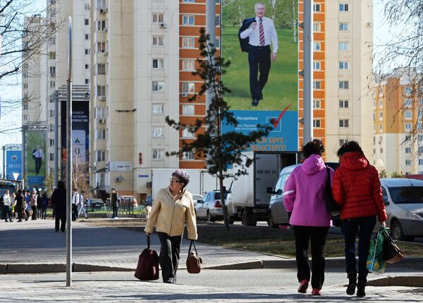 Прохожие у агитационного плаката Нурсултана Назарбаева Прохожие у агитационного плаката Нурсултана Назарбаева - Sputnik Беларусь
