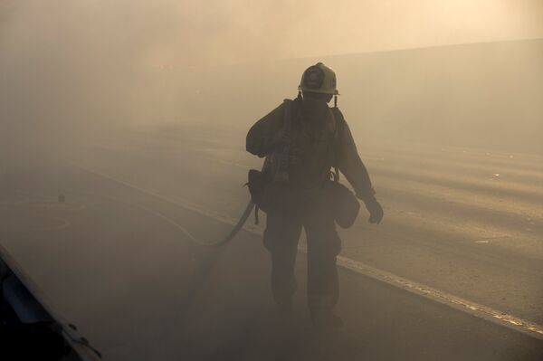 Работник пожарной службы во время тушения пожара - Sputnik Беларусь