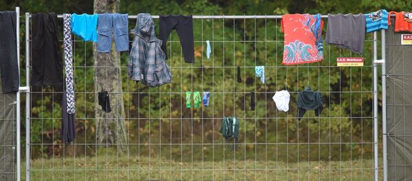Одежда мигрантов весит на заборе в лагере для беженцев в городе Целле (Германия) - Sputnik Беларусь