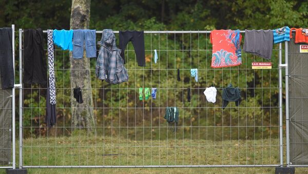 Одежда мигрантов весит на заборе в лагере для беженцев в городе Целле (Германия) - Sputnik Беларусь