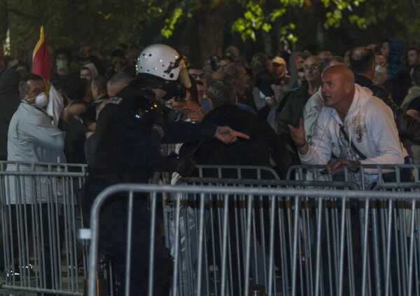 Омоновец пытается успокоить демонстрантов у здания парламента во время акций протеста в столице Черногории - Sputnik Беларусь