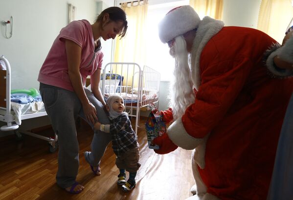 Дед Мороз вручает подарок мальчику - Sputnik Беларусь