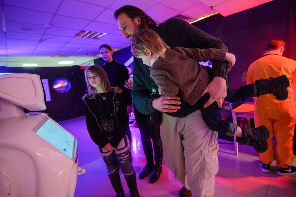 Александр Куль, директор центра экономического развития и спортивного маркетинга, с семьей общается с роботом. - Sputnik Беларусь