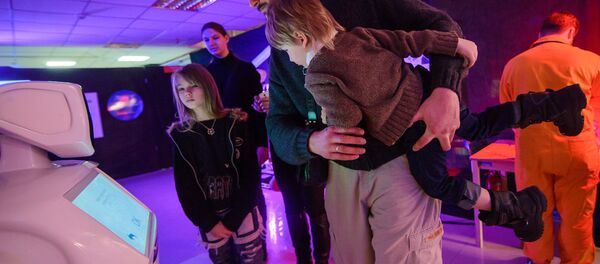 Александр Куль, директор центра экономического развития и спортивного маркетинга, с семьей общается с роботом. - Sputnik Беларусь