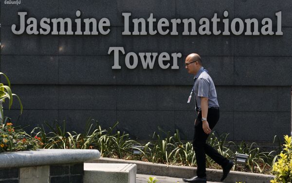 Человек проходит мимо логотипа Jasmine International Tower в Бангкоке - Sputnik Беларусь
