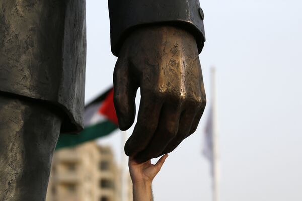 Палестинец прикасается к руке гигантской статуи Нельсона Манделы - Sputnik Беларусь