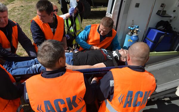 Члены аварийно-спасательной команды доставляют в машину скорой помощи пассажира - Sputnik Беларусь
