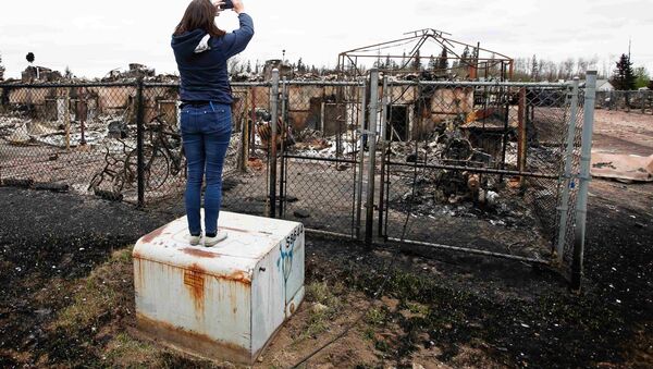 Женщина фотографирует сгоревший дом в городе Форт-Мак-Мюррей в провинции Альберта (Канада) - Sputnik Беларусь