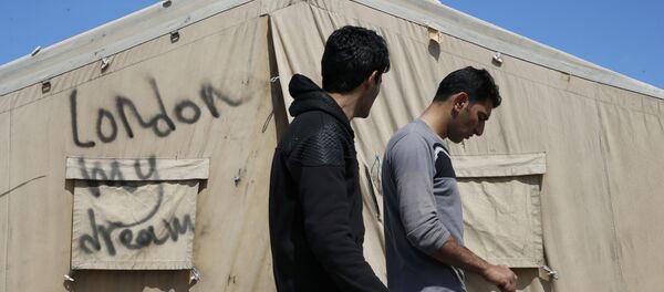 Мигранты идут мимо палатки в лагерье иммигрантов в Кале, Франция - Sputnik Беларусь