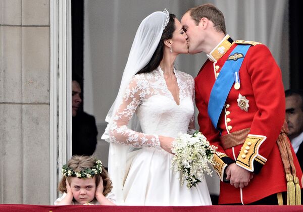 Свадебный поцелуй британской Золушки Кейт еще более популярный. Принц Великобритании Уильям целует свою уже жену, герцогиню Кембриджскую, на балконе Букингемского дворца, после свадебной церемонии 29 апреля 2011 года. Девочка внизу кадра сразу стала сенсацией в интернете. - Sputnik Беларусь