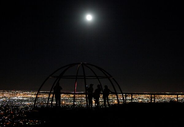 Люди наблюдают за суперлунием над утопающим в вечерних огнях Сьюдад-Хуаресом - Sputnik Беларусь