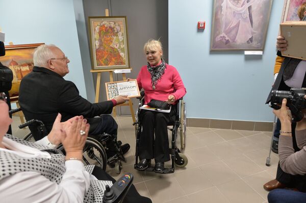 Председатель Белорусского общества инвалидов Владимир Потапенко вручает диплом участника выставки художнице из Москвы Ирине Витошинской - Sputnik Беларусь