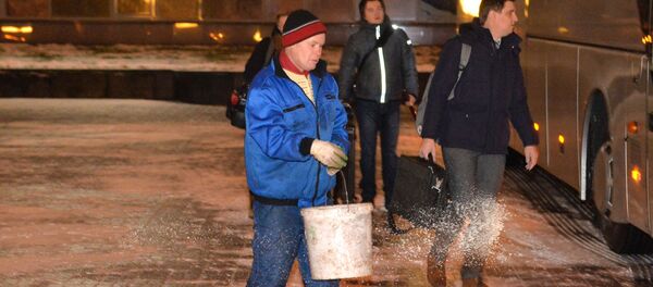 Работник ЖКХ посыпает солью скользкую плитку возле гостиницы Планета - Sputnik Беларусь