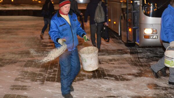 Сотрудник посыпает тротуар песчано-соляной смесью - Sputnik Беларусь