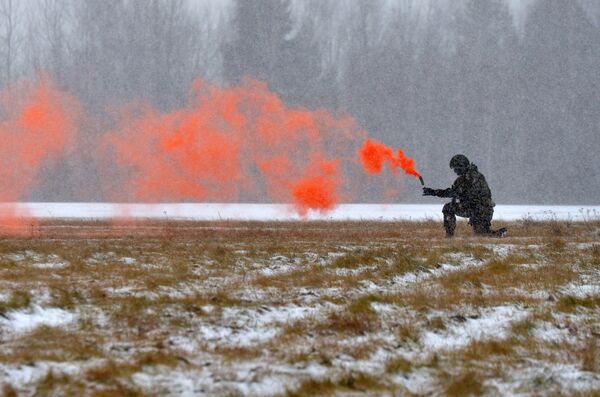 Военнослужащий Сил специальных операций цветными дымами обозначает место посадки вертолета - Sputnik Беларусь