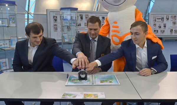 Борец Джавид Гамзатов, первый вице-президент НОК Максим Рыженков и батутист Владислав Гончаров (слева направо) гасят почтовую марку  - Sputnik Беларусь