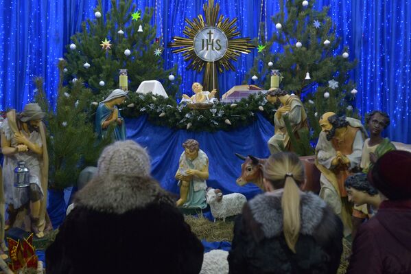 Прихожане костела святых Симеона и Елены молятся у яслей младенца Иисуса перед началом рождественской службы - Sputnik Беларусь
