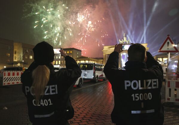 Немецкие полицейские снимают, как новогодний фейерверк взрывается рядом со скульптурой колесницы на Бранденбургских воротах во время Новогодних торжеств в Берлине, Германия. 1 января 2017 года - Sputnik Беларусь