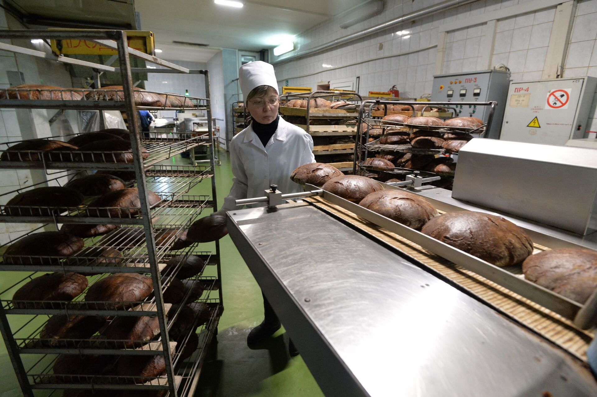 Работница хлебозавода укладывает хлеб на ленту нарезочной машины - Sputnik Беларусь, 1920, 17.06.2022