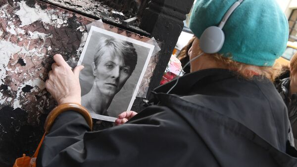 Женщина клеит портрет Дэвида Боуи возле его аппартаментов в Нью-Йорке - Sputnik Беларусь