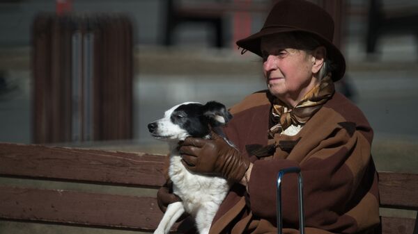Женщина сидит на скамейке с собакой на руках - Sputnik Беларусь