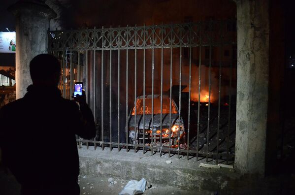 Человек фотографирует на смартфон сожженные в ходе беспорядков в Батуми машины - Sputnik Беларусь