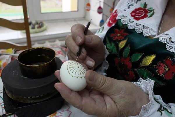 Наносятся восковые полоски и завитушки, а из них получаются цветочные узоры Наносятся восковые полоски и завитушки, а из них получаются цветочные узоры - Sputnik Беларусь