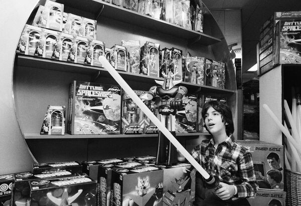 Мальчик в магазине игрушек в Нью-Йорке со световым мечом Star Wars в 1977 году. Сувениры и игрушки стали выпускать сразу после выхода первого фильма Джорджа Лукаса. - Sputnik Беларусь