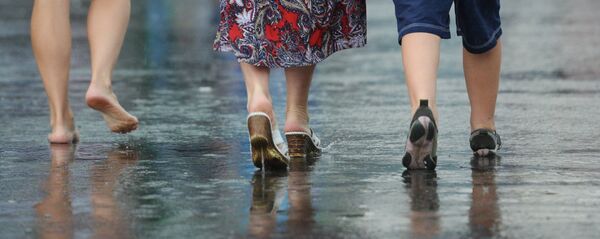 Прохожие идут по улице во время сильного дождя - Sputnik Беларусь