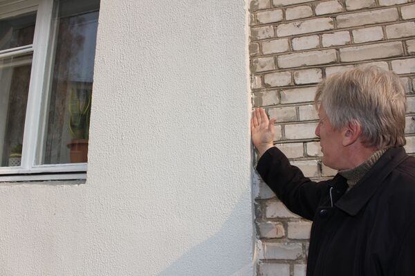 Вадим Ерошов показывает запачканные краской и штукатуркой стены, на окнах нет отливов - Sputnik Беларусь