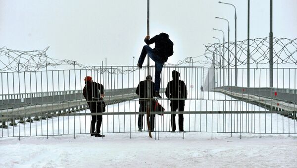 Люди перелазят через ограждение на мосту, несмотря на колючую проволоку - Sputnik Беларусь