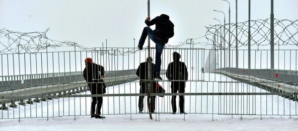 Люди перелазят через ограждение на мосту, несмотря на колючую проволоку - Sputnik Беларусь