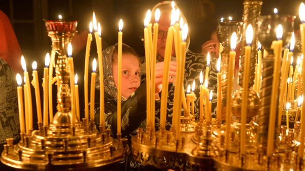 Даже самые маленькие ставят в церквях свечи на пасхальных службах - Sputnik Беларусь