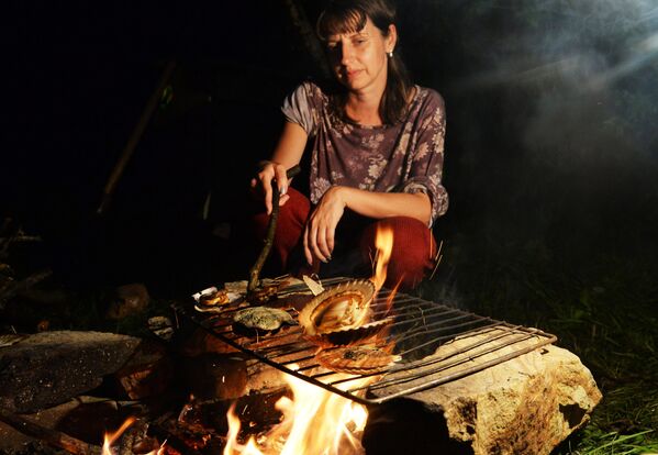 Женщина жарит моллюсков на огне на острове Путятина. - Sputnik Беларусь