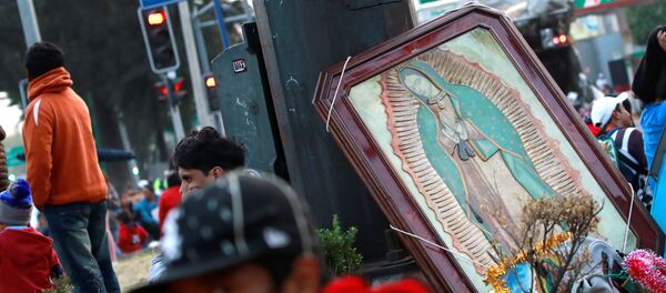 Мужчина сидит рядом с изображением Девы Гуадалупской во время ежегодного паломничества - Sputnik Беларусь