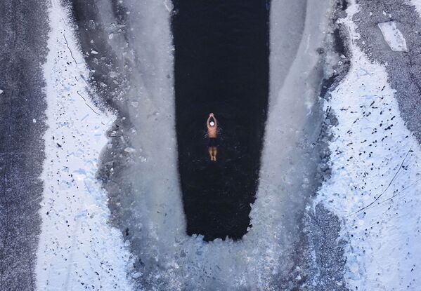 Человек плавает в частично замерзшем озере в Шэньяне, провинция Ляонин - Sputnik Беларусь