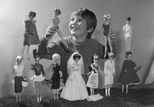 Девочка играет с куклами Барби на ярмарке игрушек в Нюрнберге, Западная Германия, 1965 год. Каждая кукла поставлялась в комплекте с несколькими сменами одежды, включая купальные костюмы, свадебные платья и вечерние платья, по цене 250 долларов. - Sputnik Беларусь