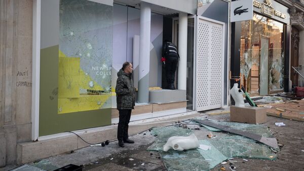 Мужчина стоит перед разбитой витриной во время демонстрации движения желтые жилеты в Париже - Sputnik Беларусь