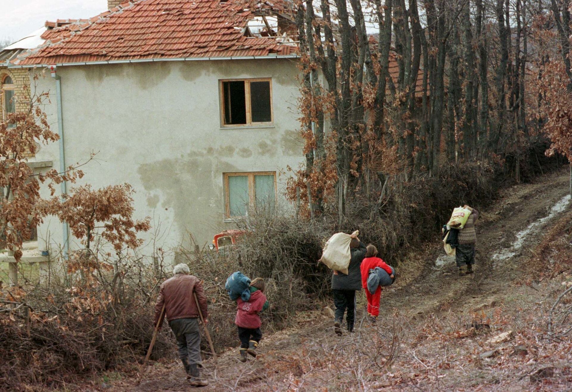 Этнические албанские беженцы возле разрушенного дома к западу от Приштины 4 марта 1999 года после обстрела сербскими вооруженными силами - Sputnik Беларусь, 1920, 24.03.2022