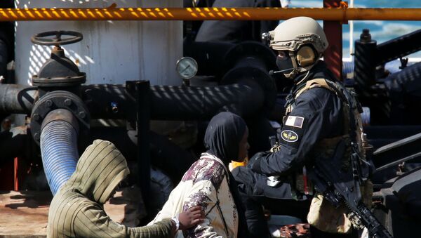 Мальтийский солдат спецназа охраняет группу мигрантов на торговом корабле Elhiblu 1  - Sputnik Беларусь