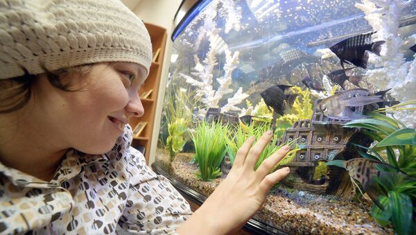 Девочка с ДЦП смотрит на рыбок, архивное фото - Sputnik Беларусь