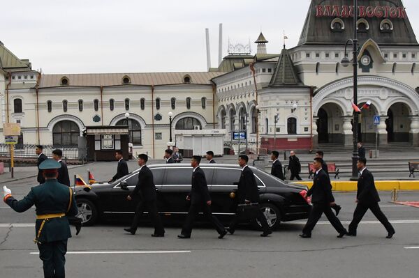 Сотрудники службы безопасности сопровождают автомобиль кортежа лидера КНДР Ким Чен Ына - Sputnik Беларусь
