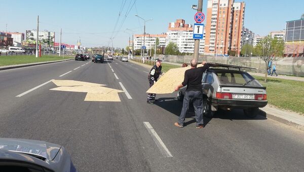 Инспекторы ГАИ помогли мужчине собрать с дороги разлетевшийся груз - Sputnik Беларусь