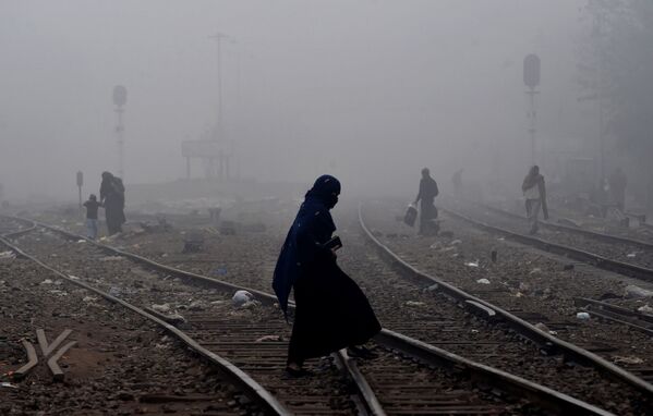 Пакистанская женщина идет по густому туману через железнодорожные пути - Sputnik Беларусь