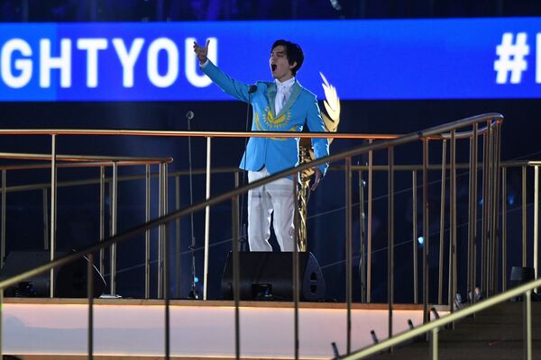 Казахстанский исполнитель Димаш вышел на сцену в пиджаке-флаге. Под его песню на арене появился флаг ЕОК. - Sputnik Беларусь