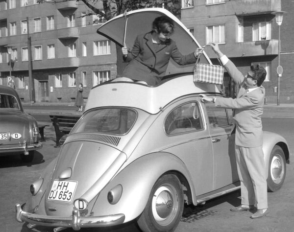 Девушка демонстрирует пластиковый контейнер, прикрепленный к крыше автомобиля Volkswagen Beetle – дополнительное место для багажа. Его представили на Международной выставке пластмасс в Дюссельдорфе, Германия, в 1959 году. - Sputnik Беларусь