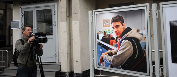 Видеооператор у фотографии погибшего на Украине фотокорреспондента Андрея Стенина у здания МИА Россия сегодня - Sputnik Беларусь