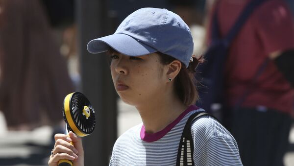 Женщина держит портативный вентилятор, чтобы избежать жары в Токио - Sputnik Беларусь