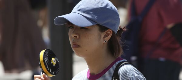 Женщина держит портативный вентилятор, чтобы избежать жары в Токио - Sputnik Беларусь